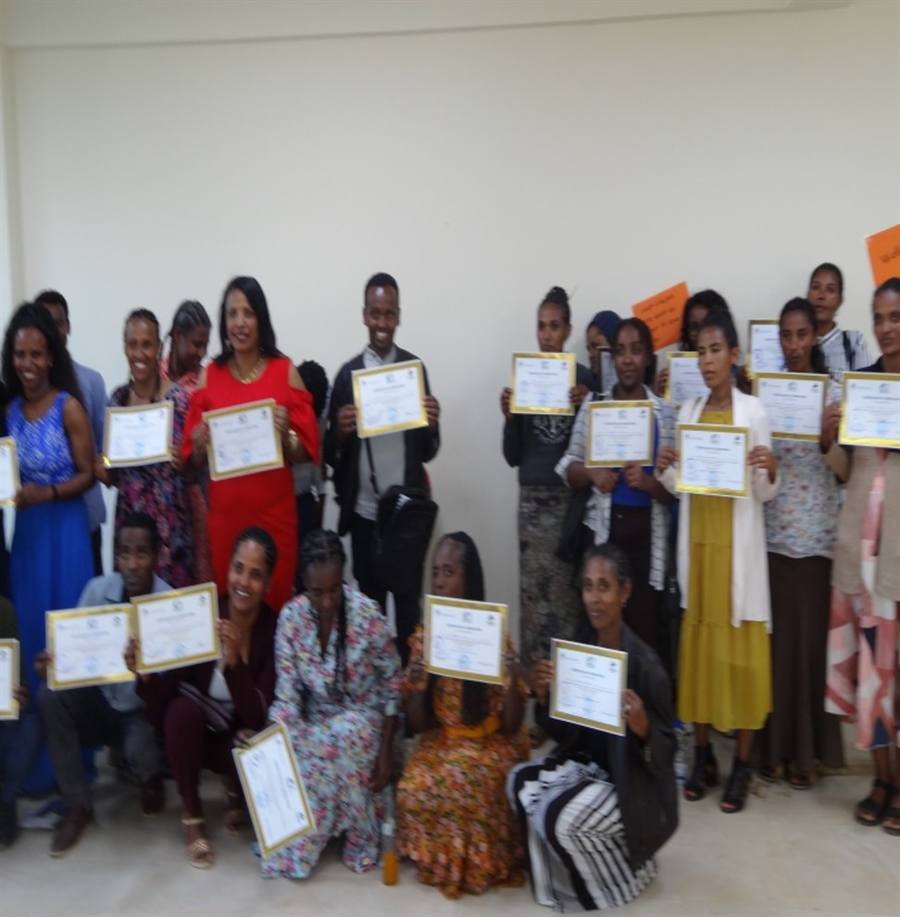 Teachers proudly hold up their certificates after completing a training programme.